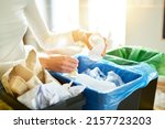 Woman putting empty plastic bottle in recycling bin in the kitchen. Person in the house kitchen separating waste. Different trash can with colorful garbage bags.