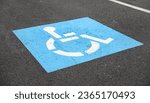 Small photo of blue handicap parking symbol against asphalt background, representing accessible spaces for disabled individuals, inclusivity, and equal rights