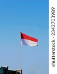 Small photo of The red and white Indonesian flag flutters against a blue sky background