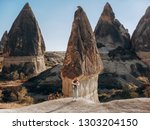 Small photo of fashion girl in yellow helmet pack something in backpack on view of Rock like mashrooms. landscape of valley at Cappadocia.