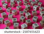 Wooden cubes with letters scattered randomly on a pink background