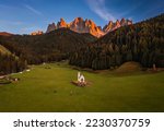 Val Di Funes, Dolomites, Italy - Aerial view of the beautiful St. Johann Church (Chiesetta di San Giovanni in Ranui) at South Tyrol with the Italian Dolomites in warm sunset colors at background 