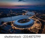 Budapest, Hungary - Aerial skyline of Budapest at dusk, including illuminated National Athletics Centre, Rakoczi bridge over River Danube and MOL Campus building at background with colorful sunset sky