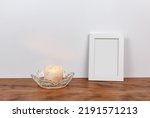 Minimalist still life of a customizable picture frame and Himalayan salt lit candle. Wood and white background