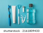 Toothbrush, tongue cleaner, floss, toothpaste tube and mouthwash on blue background with copy space. Flat lay. Dental hygiene. Oral care kit. Dentist concept.