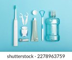 Small photo of Toothbrush,electric toothbrush,tongue cleaner, floss, toothpaste tube and mouthwash on blue background with copy space. Flat lay. Dental hygiene. Oral care kit. Dentist concept.Dental care.