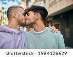 Young gay couple hugging and kissing at the city.