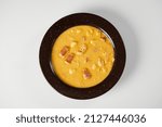 Small photo of Mote pata is a traditional ecuadorian soup made from mote, pork, sausage and sambo seeds. It’s served on a white plate with a white background.