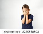 Little girl covering her eyes with her hands. Portrait of a girl cover her face, white background with copy space