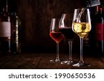 Wine tasting. Whte wine pouring into glass on background with selection of red, white and rose wines in glasses and bottles