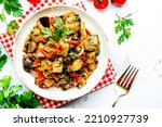 Small photo of Vegetable stew, saute or caponata. Stewed eggplant with paprika, tomatoes, spices and herbs. White kitchen table background, top view, copy space