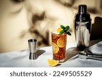 Small photo of Long Island ice tea cocktail with vodka, rum, tequila, gin, liquor, lemon juice, cola and ice, garnished with lemon slice and mint in highball glass. Beige background, hard light