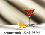Small photo of Martinez alcoholic cocktail drink with red vermouth, liqueur, orange bitter, zest and ice. Light beige background, hard light, shadow pattern, copy space