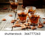 Italian amaretto liqueur with dry almonds on the old wooden background, selective focus