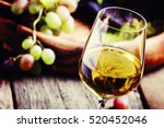 White wine in a glass with fall grapes, old wooden background, selective focus