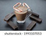 Small photo of A delicious coffee with candy canes and dark chocolate bars on a gray background