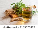 Small photo of Dandelion herbal tea in mug, dandelion leaves and roots on cutting board. Medicinal plant dandelion (Taraxacum officinale) is used in herbal medicine and healthy nutrition