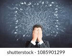 Businessman covering face on chalkboard background with drawn arrows. Risk and confusion concept 