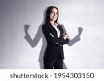 Leadership and power concept with confident businesswoman on her shadow background on light wall