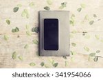 Blank black smartphone with diary on wooden table with leaves, mock up