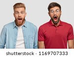 Friendship and emotions concept. Stunned emotive two men keep jaw dropped, wonder seasonal discounts and prices, stand next to each other, have trendy haircuts and beards, isolated on white.
