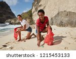 Small photo of Campaign for cleaning our environment. Happy diverse women pick up plastic bottles, fight against environmental problems, pose on seashore outdoor. Nature catastrophy and defilement concept.