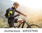 People, sports, active lifestyle and modern technology. Outdoor picture of cyclist on booster bike using navigator on smart phone, exploring map and searching GPS coordinates while biking in mountains