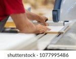 production, manufacture and woodworking industry concept - carpenter working with sliding panel saw and sawing fibreboard at furniture factory workshop