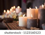 Closeup of burning candles spreading aroma on table in a spa room. Beautiful composition with grey and white candles for spa treatment. Zen and relax concept.