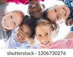 Closeup face of happy multiethnic children embracing each other and smiling at camera. Team of smiling kids embracing together in a circle. Portrait of young boy and pretty girls looking at camera.