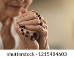 Old wrinkled hands holding a rosary. Closeup of christian senior woman hands holding rosary beads and crucified cross while praying God. Mature catholic lady holding black rosary and praying.
