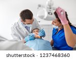 medicine, dentistry and healthcare concept - dentist with mouth mirror and probe checking for kid patient teeth at dental clinic