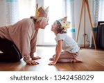 A portrait of small girl with grandmother having fun at home.