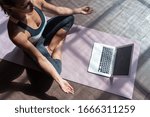 Top view young sporty slim woman coach internet video online training hatha yoga instructor modern laptop screen meditate Sukhasana posture relax breathe easy seat pose gym healthy lifestyle concept.