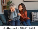 Small photo of Caring daughter comforting frustrated unhappy senior woman. Loving adult granddaughter talking to sad old grandmother and comforting her. Upset widowed woman with headache consoled by her daughter.