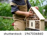 Obscured small child playing with bug and insect hotel in garden, sustainable lifestyle.