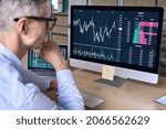 Small photo of Crypto trader investor analyst looking at computer screen analyzing financial graph data on pc monitor, thinking of online stock exchange market trading investment global risks, over shoulder view.