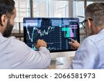 Small photo of Two traders brokers stock exchange market investors discussing crypto trading charts growth using pc computer pointing at screen analyzing financial risks, investment profit forecast. Over shoulder