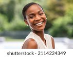 Portrait of smiling middle aged african woman looking at camera. Cheerful black mid adult woman smiling outdoor. Close up face of beautiful black lady laughing at park.