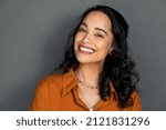 Close up face of young woman with beautiful smile isolated on grey wall with copy space. Successful multiethnic girl. Latin woman looking at camera against gray wall with a big whitening teeth smile.