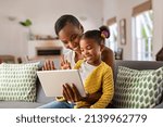 Small photo of Smiling ethnic mother and funny daughter on video call using digital tablet at home. African american mature mother and little girl using digital tablet while making video call and waving hello.