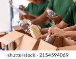 Small photo of charity, donation and volunteering concept - close up of international group of happy smiling volunteers packing food in boxes at distribution or refugee assistance center