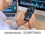 Crypto trader investor broker using smartphone app analyzing financial data stock market price on cell phone, checking online trading platform application, buying cryptocurrency, over shoulder view.