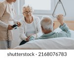 Small photo of Senior patient gets up from the hospital bed by helping himself with a special handle