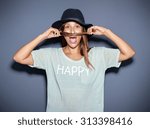 Small photo of Playful casual fashionable young woman making a pretence moustache with a strand of her long hair as she poses for the camera