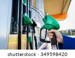object, fuel, oil, tank and transport concept - close up of hand holding gasoline hose at gas station