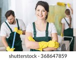 Smiling cleaning lady in uniform and yellow rubber gloves