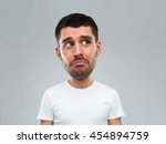 emotion, facial expressions and people concept - sad young man in white t-shirt over gray background looking up (funny cartoon style character with big head)