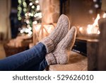 Feet of unrecognizable woman in socks by the Christmas fireplace