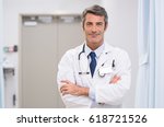 Small photo of Portrait of proud doctor with stethoscope around his neck at medical clinic. Happy smiling senior doctor at hospital lobby. Mature man feeling confident after a major operation and looking at camera.